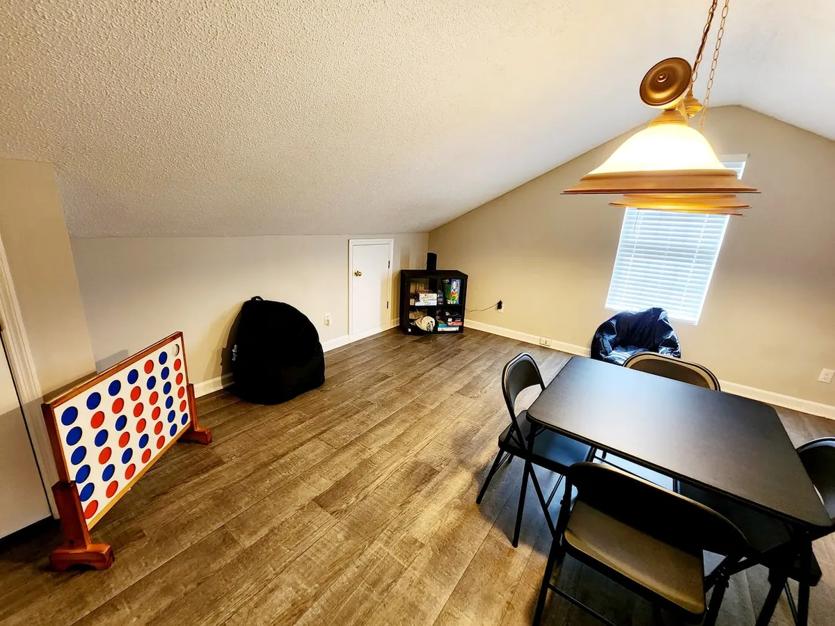 A playful and relaxed indoor game room with a dining table, bean bag chair, Connect Four game board, and shelves stocked with games—inviting for family game nights and laughter-filled gatherings.