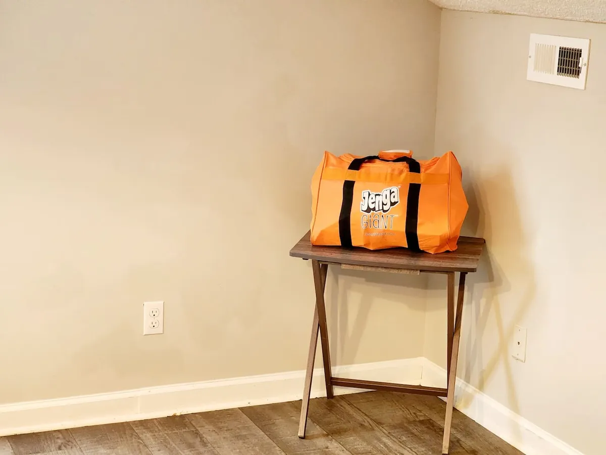 A rustic wooden table set with a bright orange bag, ready for a game night, with a playful and communal atmosphere. The minimal decor emphasizes an environment built for interaction, competition, and shared enjoyment.