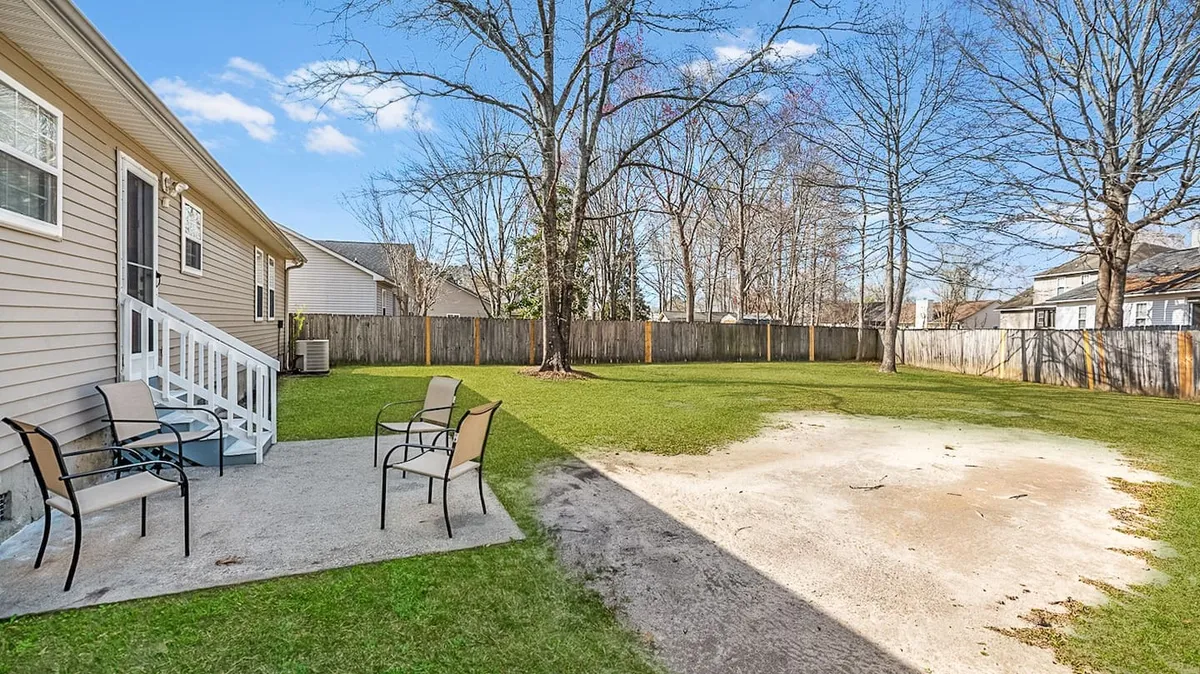 An outdoor patio area overlooking a green lawn with a tree in the background. The patio setup invites relaxation and gatherings, making it suitable for morning coffee, evening stargazing, or al fresco dining.